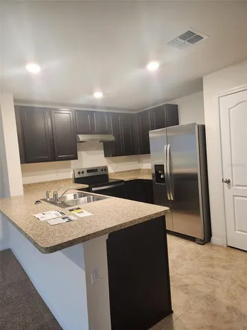 a kitchen with kitchen island a counter top space a sink and a refrigerator