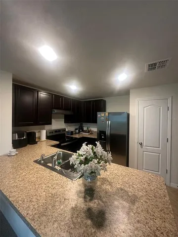 a kitchen with granite countertop a refrigerator and a sink