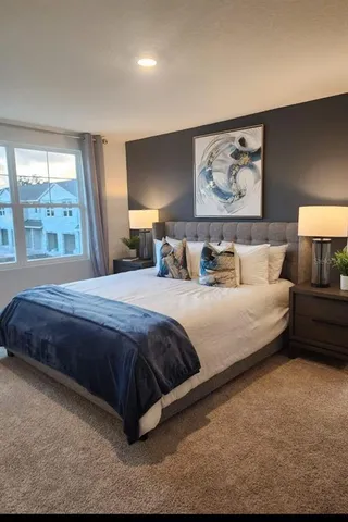 a bedroom with a bed a lamp and large window