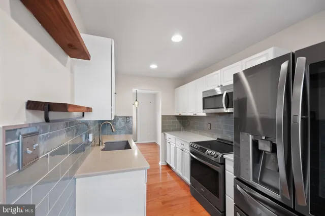 a kitchen with stainless steel appliances granite countertop a refrigerator a stove and a sink