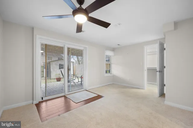 an empty room with chandelier fan and windows