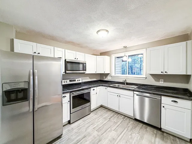 a kitchen with granite countertop white cabinets and stainless steel appliances
