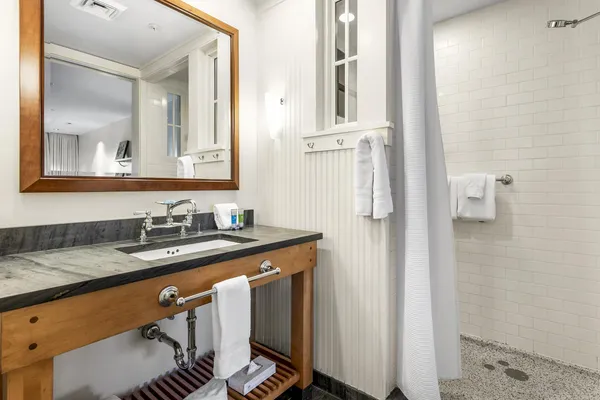 a bathroom with a granite countertop sink a mirror and a shower