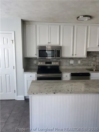 a kitchen with stainless steel appliances granite countertop a stove a sink and a microwave