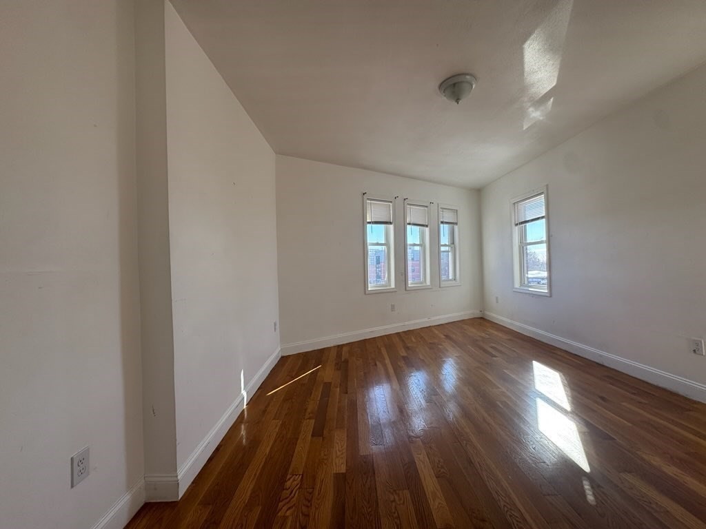 176 Ferry Street, Unit 3L Everett, MA 02149 - Photo 2 of 13 an empty room with wooden floor and windows