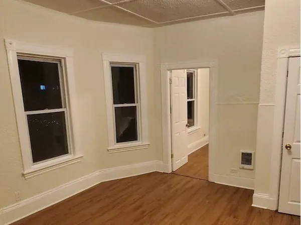 a view of an empty room with wooden floor and closet