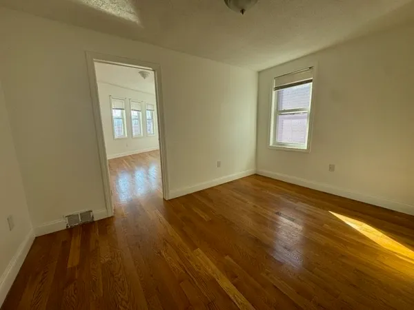 a view of an empty room and wooden floor and a window
