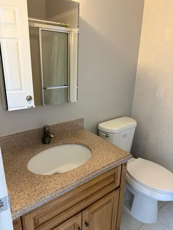 a bathroom with a granite countertop sink and a toilet