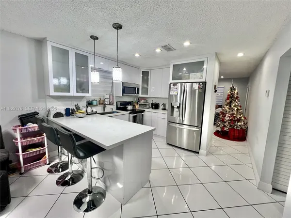 a kitchen with stainless steel appliances kitchen island granite countertop a stove refrigerator and cabinets