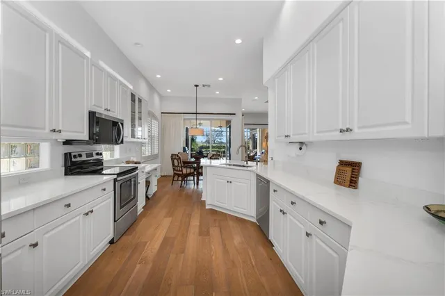 a kitchen with white cabinets stainless steel appliances a sink and a counter top space