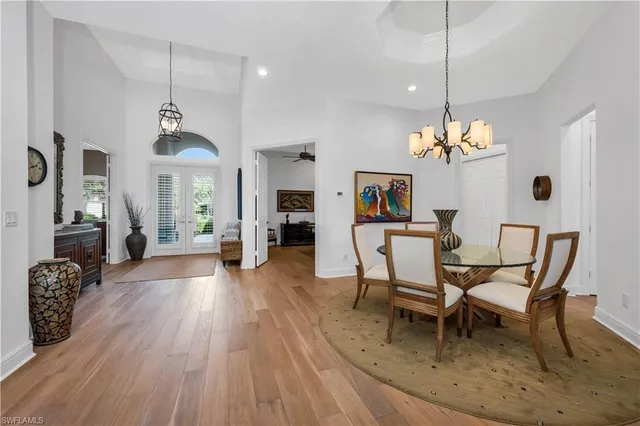 a dining room with wooden floor a chandelier a wooden table and chairs