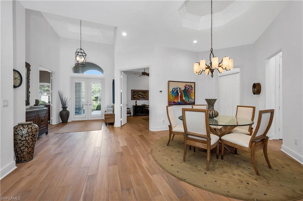 1033 Tierra Lago Way Naples, FL 34119 - Photo 7 of 27 a dining room with wooden floor a chandelier a wooden table and chairs
