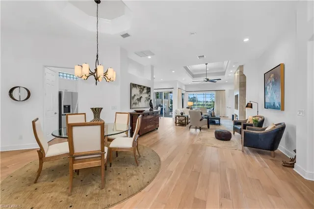 a view of a dining room and livingroom with furniture wooden floor a chandelier