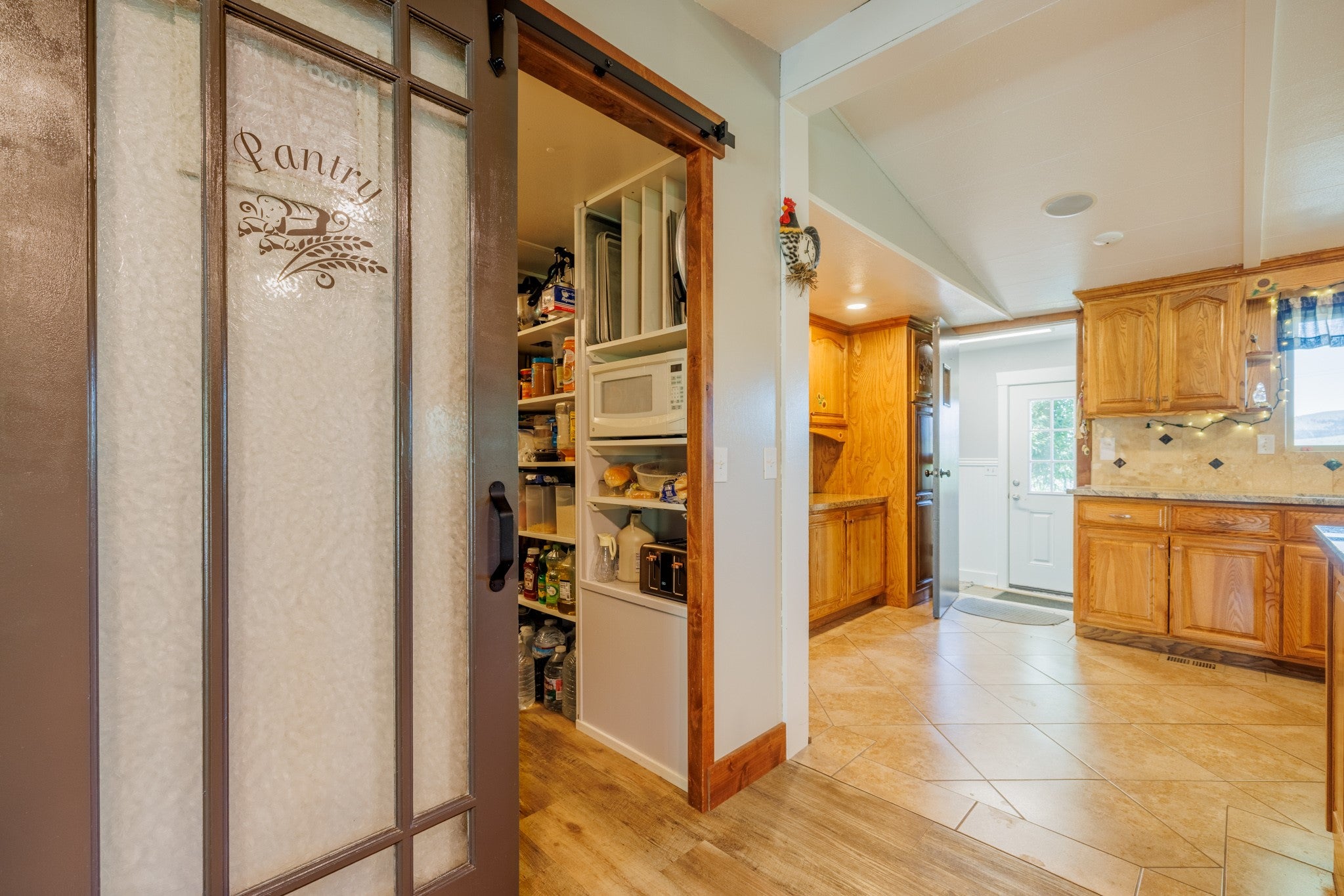 58 Gilman Road Garrison, MT 59731 - Photo 29 of 91 Kitchen with vaulted ceiling, decorative backsplash, white microwave, light stone counters, and a barn door