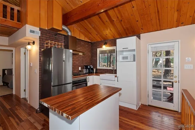 a living room with stainless steel appliances furniture a refrigerator and wooden floor