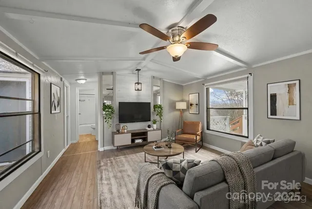 a living room with furniture a ceiling fan and a flat screen tv