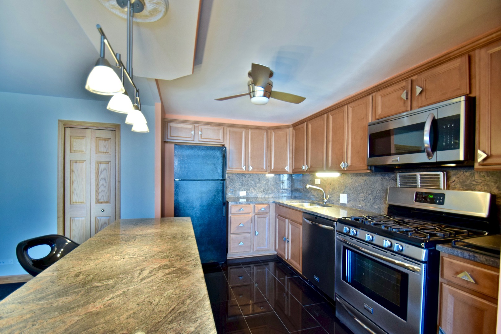 400 East Randolph Street, Unit 3326 Chicago, IL 60601 - Photo 3 of 19 a kitchen with stainless steel appliances granite countertop a stove top oven a sink dishwasher a microwave oven and a dining table with wooden floor