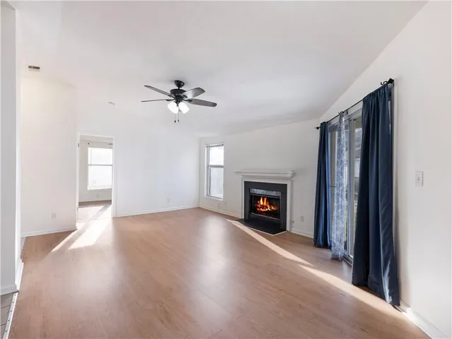 an empty room with fan fireplace and windows