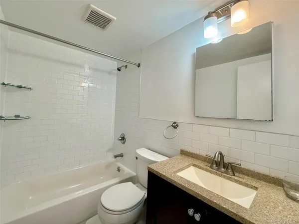 a bathroom with a granite countertop sink toilet a shower and a mirror