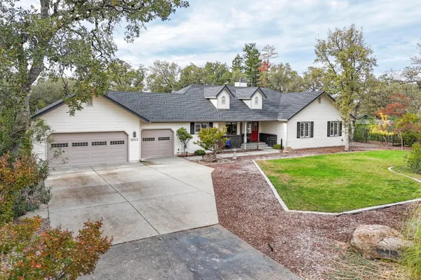 a front view of a house with a garden and trees