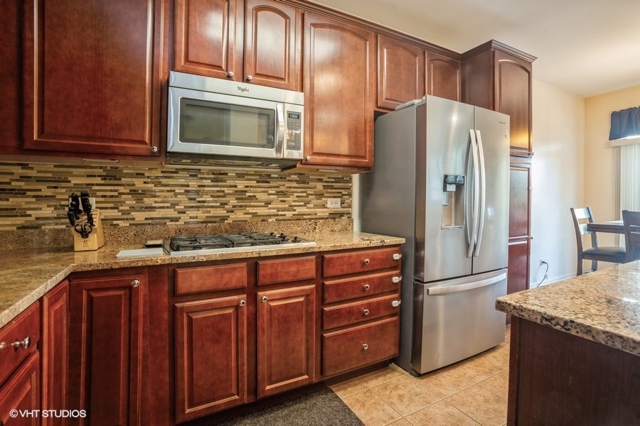 5426 Cloverdale Road Hanover Park, IL 60133 - Photo 6 of 22 a kitchen with granite countertop stainless steel appliances and wooden cabinets