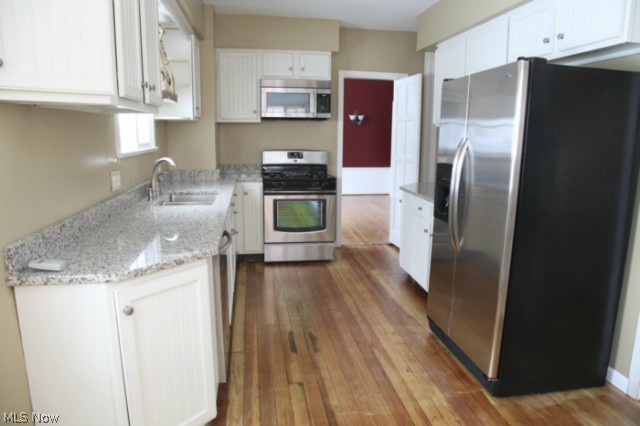 3712 Traynham Road Beachwood, OH 44122 - Photo 9 of 25 The remodeled eat in kitchen features: refaced cabinets & knobs, wood floors-several layers of vinyl were removed to find continuous wood floors that were refinished, slab granite counters & backsplash, stainless under mount sink & faucet, stainless built in microwave, dishwasher, side by side refrigerator, gas stove, ceiling fan, window viewing to back yard, door to back patio & breakfast nook.