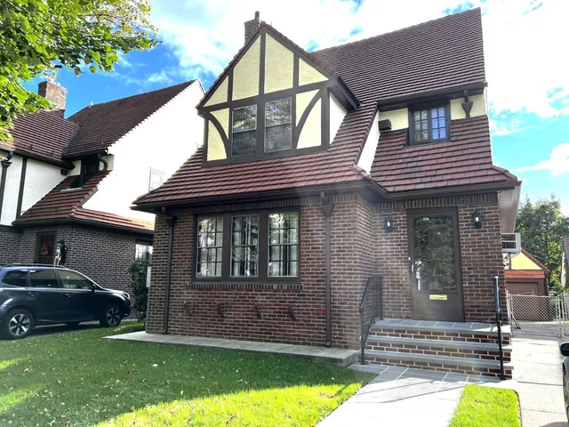 a front view of a house with a garden and trees