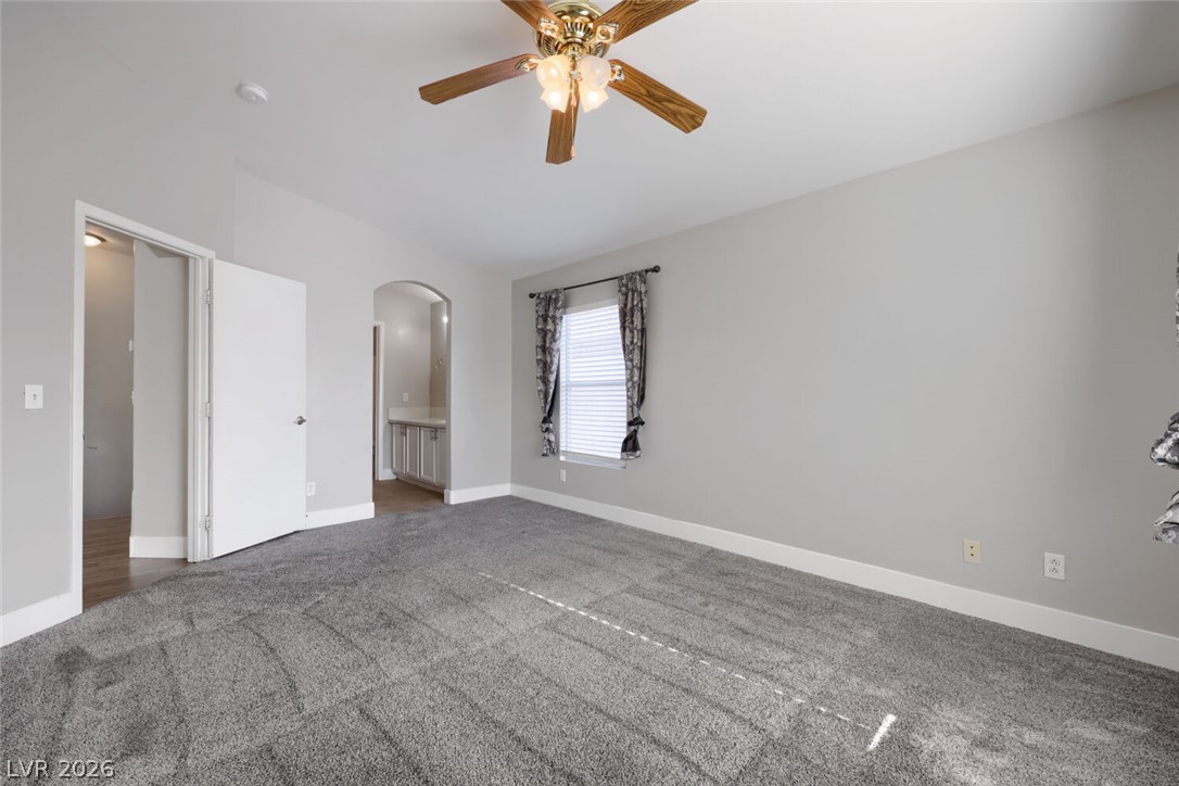 5985 High Steed Street, Unit 101 Henderson, NV 89011 - Photo 18 of 38 A spacious bedroom features plush carpeting and a classic ceiling fan, offering a comfortable retreat.