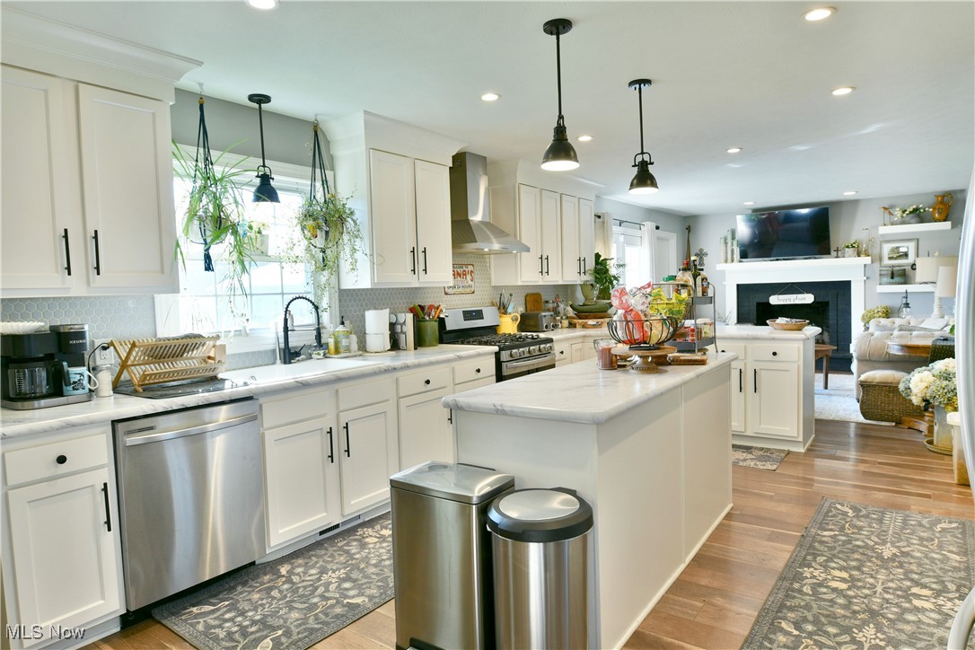 5558 Pierce Road Northwest Warren, OH 44481 - Photo 19 of 50 Kitchen with pendant lighting, appliances with stainless steel finishes, wall chimney range hood, and white cabinetry