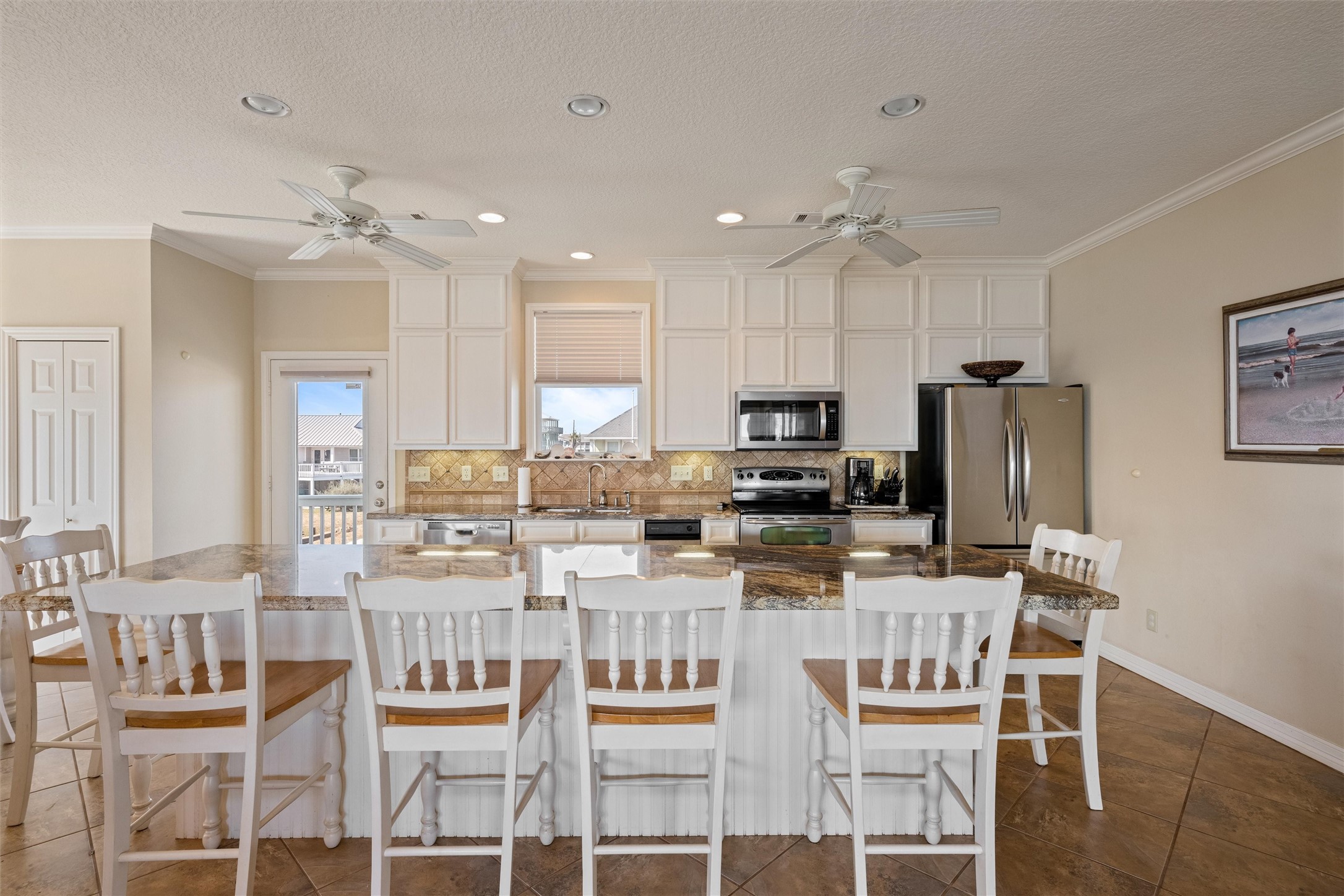 3125 James Street Crystal Beach, TX 77650 - Photo 15 of 45 a kitchen with stainless steel appliances kitchen island granite countertop a dining table chairs refrigerator and sink