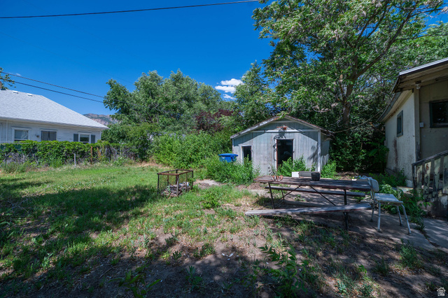 1256 24th Street Ogden, UT 84401 - Photo 22 of 34 Expansive backyard featuring a detached shed structure, mature trees, and existing concrete patio space