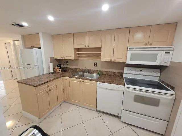 a kitchen with granite countertop white cabinets and white appliances