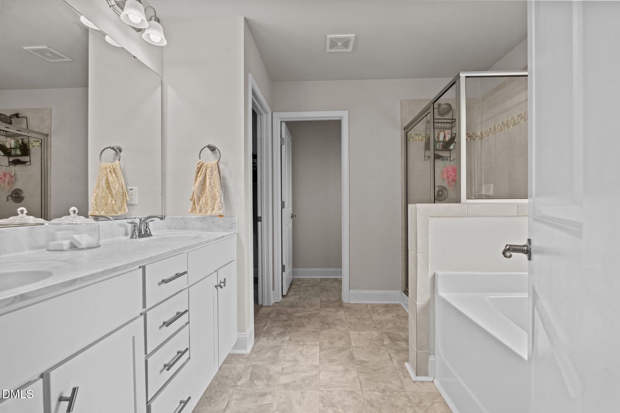 111 Spring Flowers Drive Cameron, NC 28326 - Photo 20 of 31 a bathroom with a double vanity sink a mirror and a bathtub
