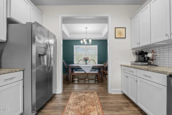 a living room with stainless steel appliances furniture a rug and a kitchen view