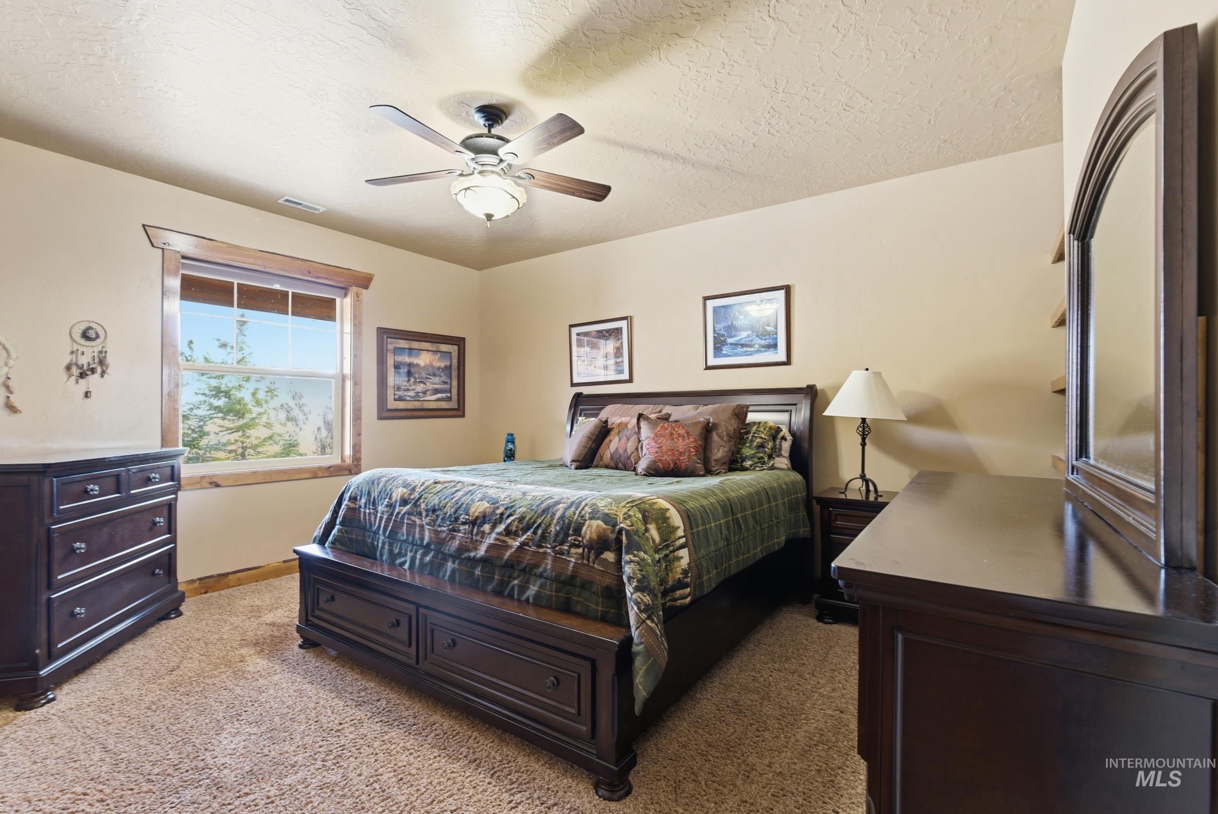 2538 West Mountain Road Donnelly, ID 83615 - Photo 20 of 50 Carpeted bedroom featuring a large window with wood trim, a ceiling fan with integrated lighting, and neutral wall tones