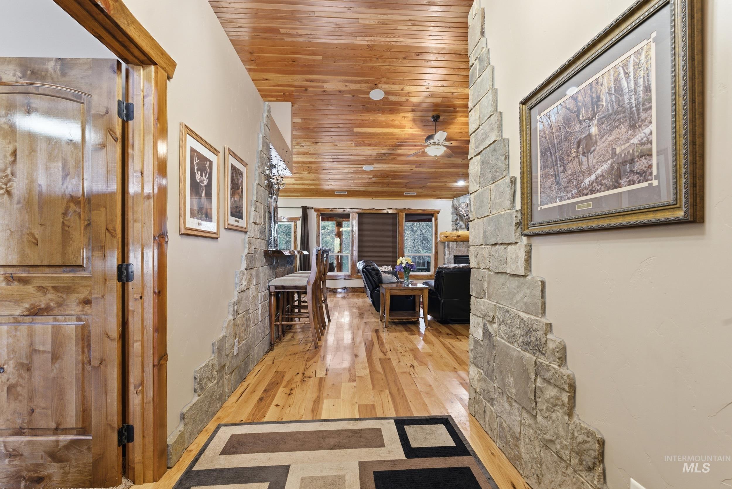 2538 West Mountain Road Donnelly, ID 83615 - Photo 23 of 50 Hallway featuring wood-finish flooring, a wood-paneled ceiling, and stone-accented walls
