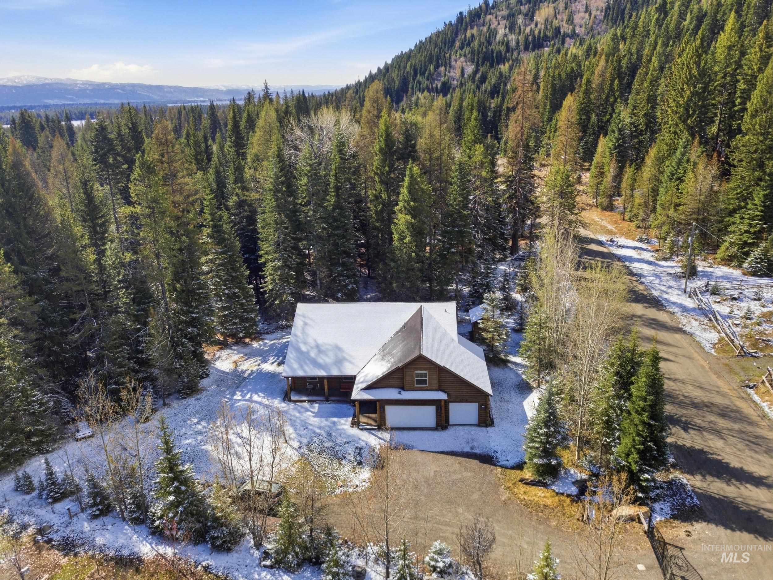 2538 West Mountain Road Donnelly, ID 83615 - Photo 3 of 50 Wood-sided residence featuring a snow-dusted gabled roof and an attached two-car garage