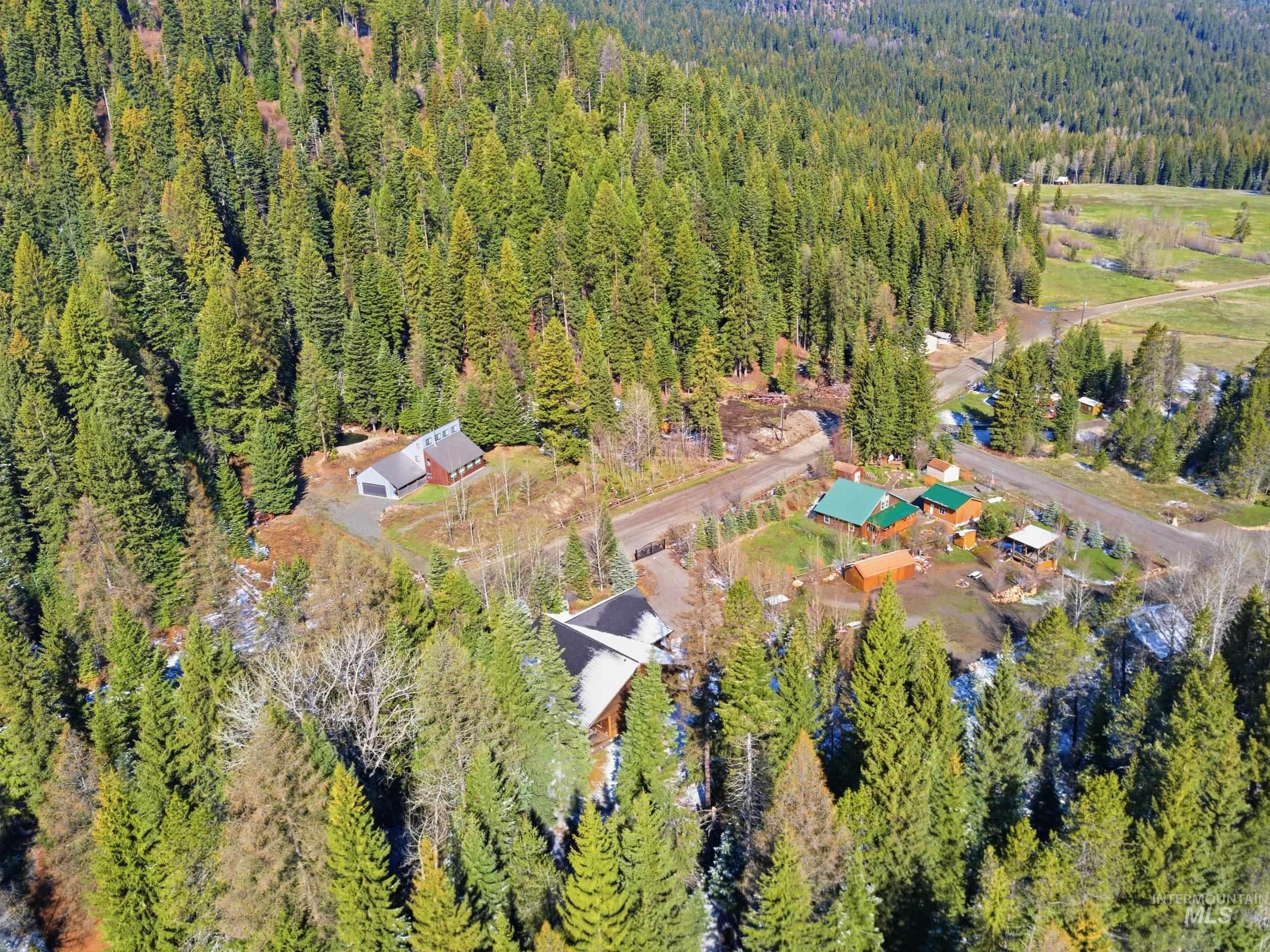 2538 West Mountain Road Donnelly, ID 83615 - Photo 47 of 50 Wooded acreage featuring multiple structures, including a primary residence with a dark roof and a secondary residence with a green metal roof