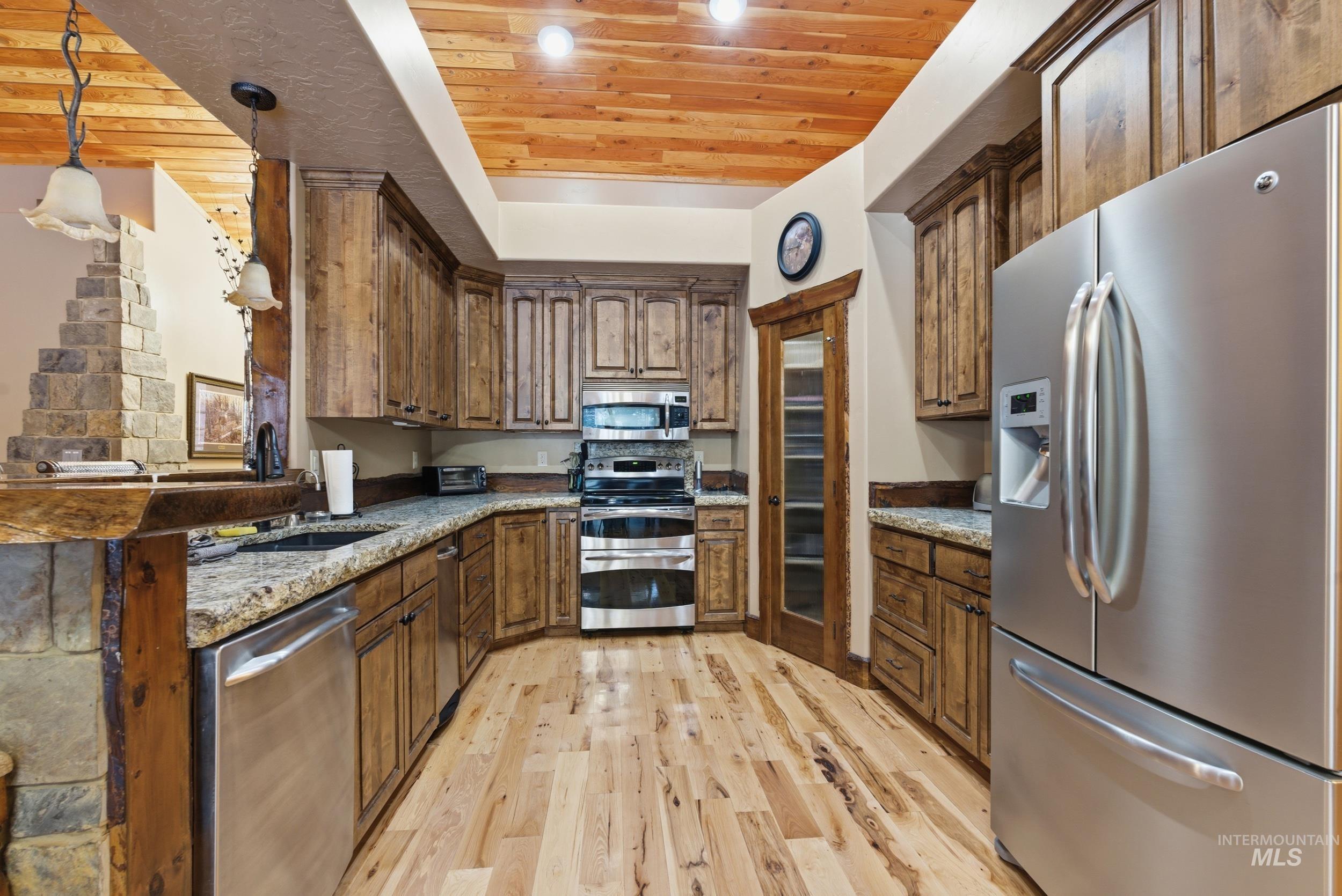 2538 West Mountain Road Donnelly, ID 83615 - Photo 9 of 50 Kitchen featuring wood-finish flooring, granite countertops, and stainless steel appliances