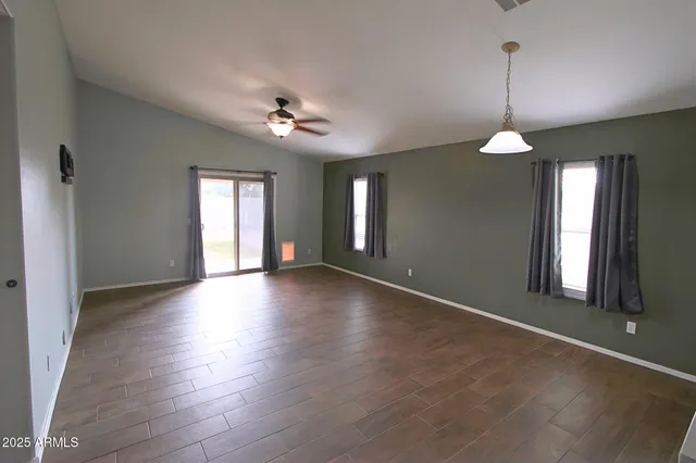a view of an empty room with window and wooden floor