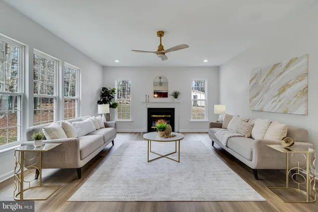 a view of a hallway to a livingroom with wooden floor and furniture