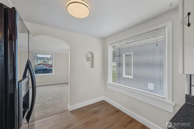 a view of an empty room with wooden floor and a window