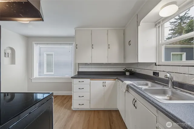 a kitchen with granite countertop a sink a stove and cabinets