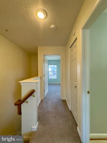 a view of a hallway with wooden floor and a bathroom