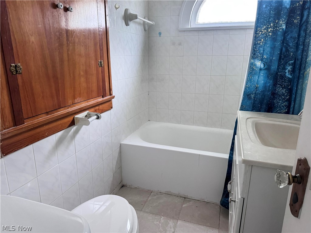 7121 North Lima Road Youngstown, OH 44514 - Photo 27 of 37 Bathroom featuring a white bathtub, ceramic wall tiling, and a white vanity with an integrated sink