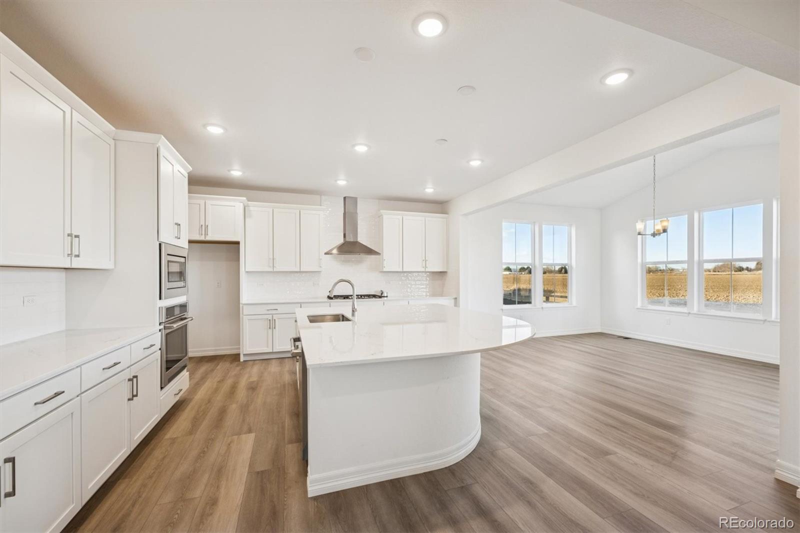 6120 Oban Road Timnath, CO 80547 - Photo 6 of 22 a large white kitchen with wooden floors and stainless steel appliances
