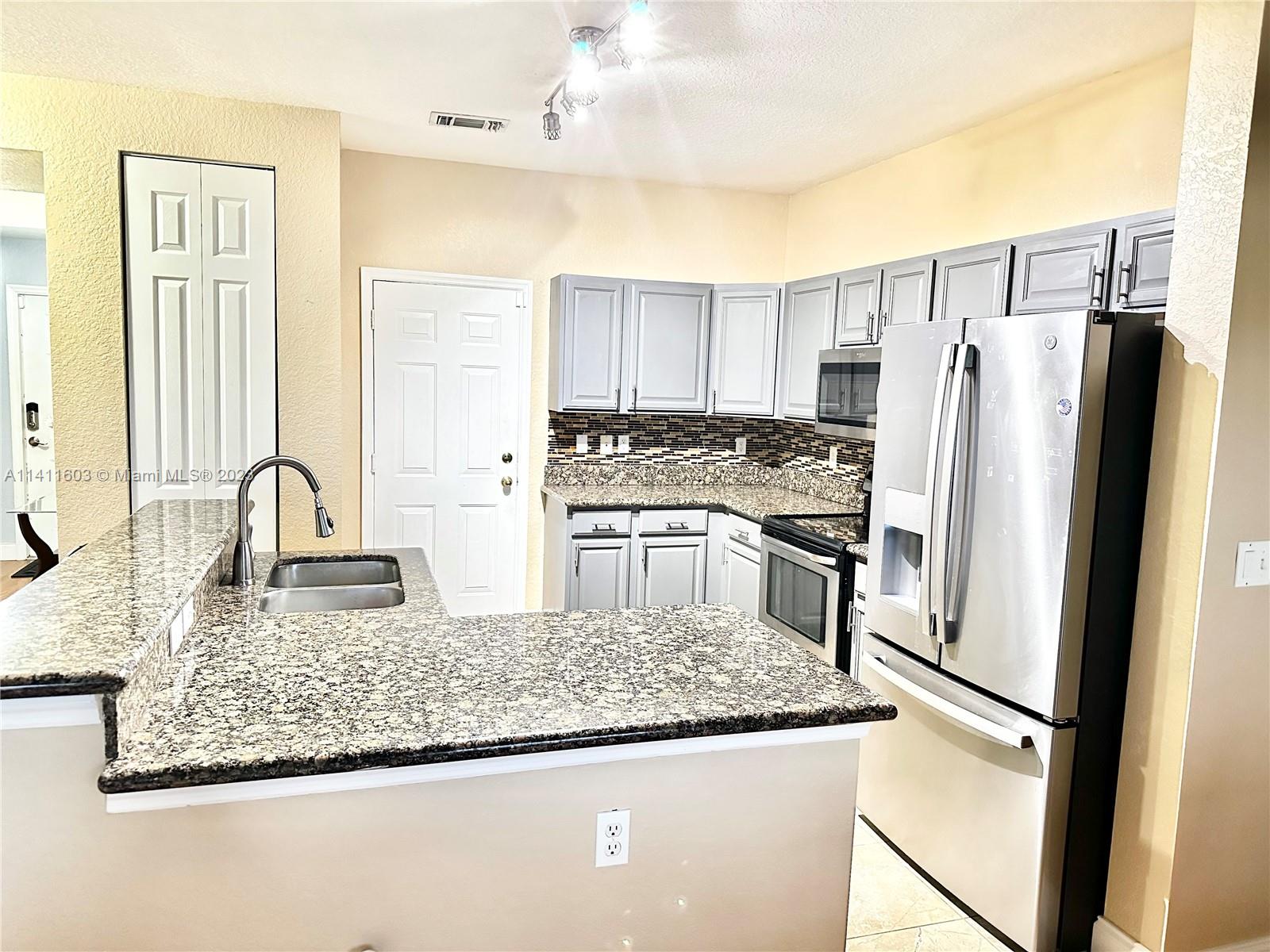 4322 Emerald Vista Lake Worth, FL 33461 - Photo 3 of 40 a kitchen with stainless steel appliances granite countertop a refrigerator a stove and a sink with wooden floor