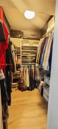 a view of walk in closet with clothes and shoes