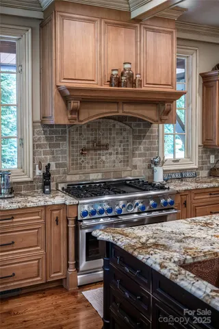 a kitchen with granite countertop a sink a stove and cabinets