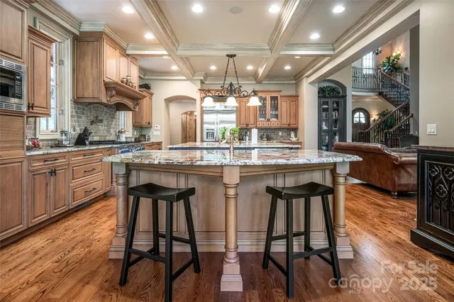 a kitchen with stainless steel appliances granite countertop table chairs sink and wooden floor